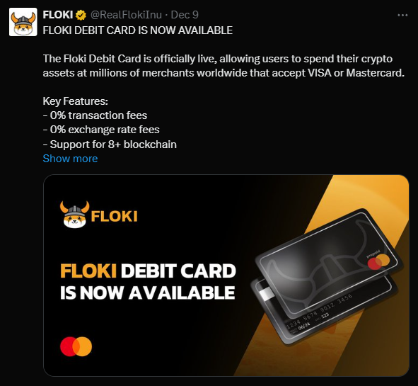 A imagem apresenta um cartão de débito Floki, destacado com o logotipo da Floki Inu, que exibe um fundo gradiente em tons escuros. O texto "FLOKI DEBIT CARD IS NOW AVAILABLE" está em destaque, anunciando a disponibilidade do cartão. O canto inferior esquerdo contém o símbolo do Mastercard. A imagem comunica que o cartão permite aos usuários gastar seus ativos de criptomoeda em milhões de comerciantes que aceitam cartões Visa ou Mastercard, além de ressaltar características como isenção de taxas de transação e suporte a mais de 8 blockchains.